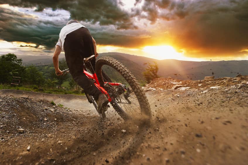 man on mountain bike rides on the trail on a stormy sunset.